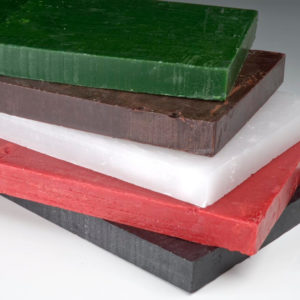 10 lbs. pieces of wax stacked on top of each other in a variety of colors: green, red, black, etc.