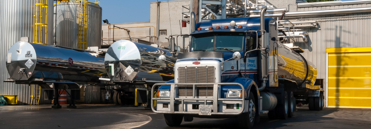 10-wheeler truck being loaded with a tanker at a factory. 